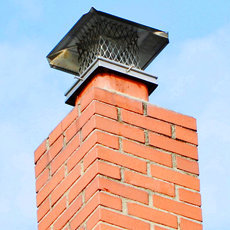 Red-brick chimney stack fitted with a metal bird guard or cowl