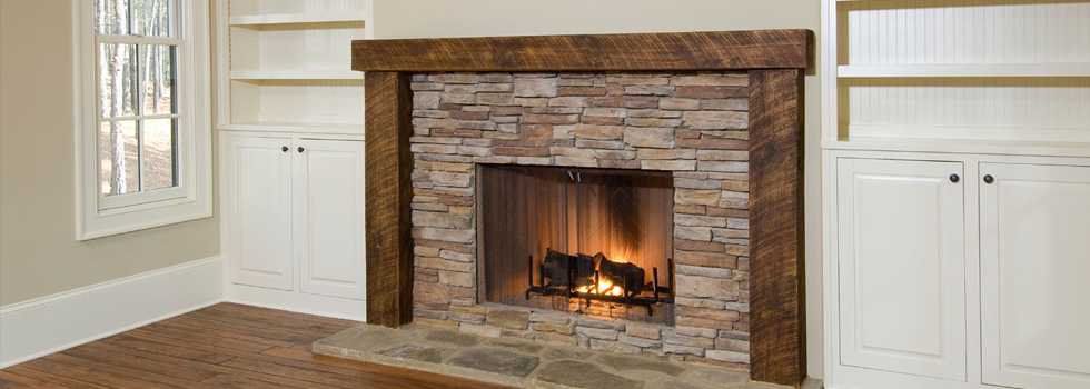 Bright domestic fireplace with a stone surround, wooden mantel and a lit fire